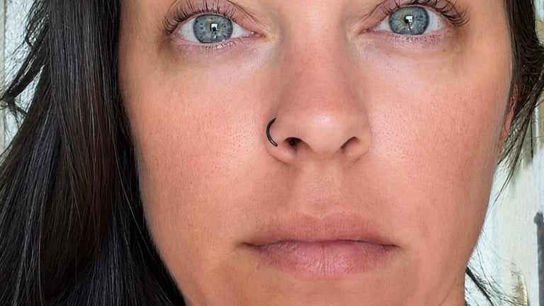 Close-up portrait of a woman with blue eyes, dark hair, and neutral expression looking directly at camera