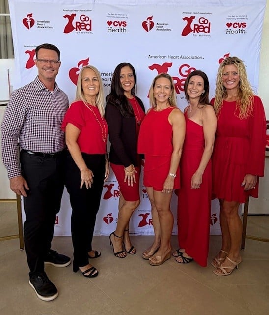 Six people posing together at an American Heart Association event with CVS Health branding on the backdrop