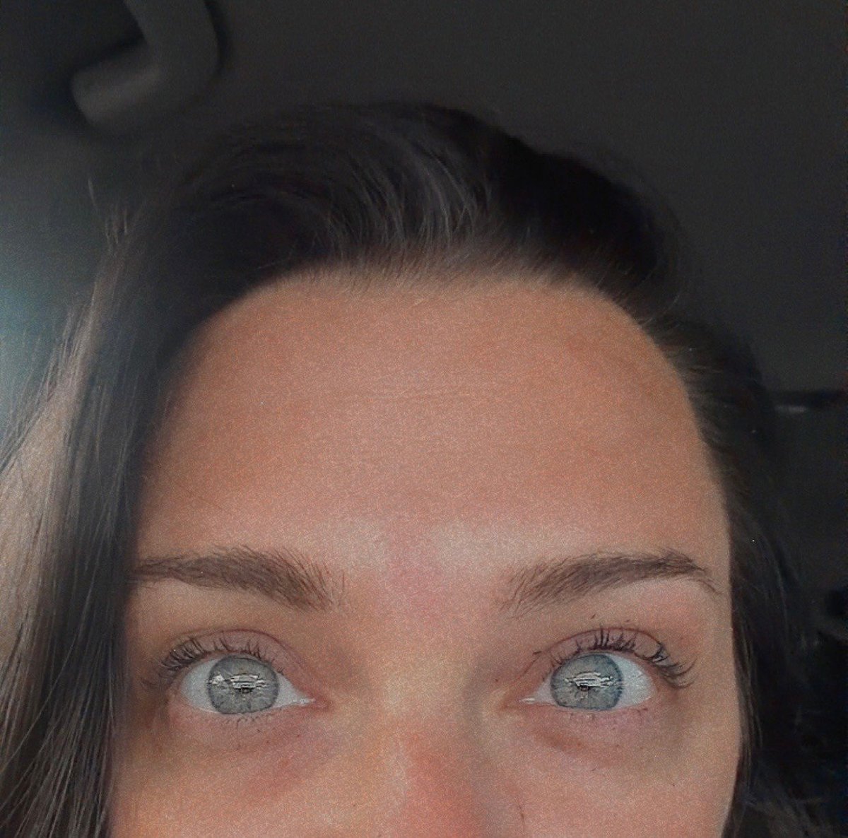 Close-up of a womans face showing her eyes and forehead with dark hair pulled back